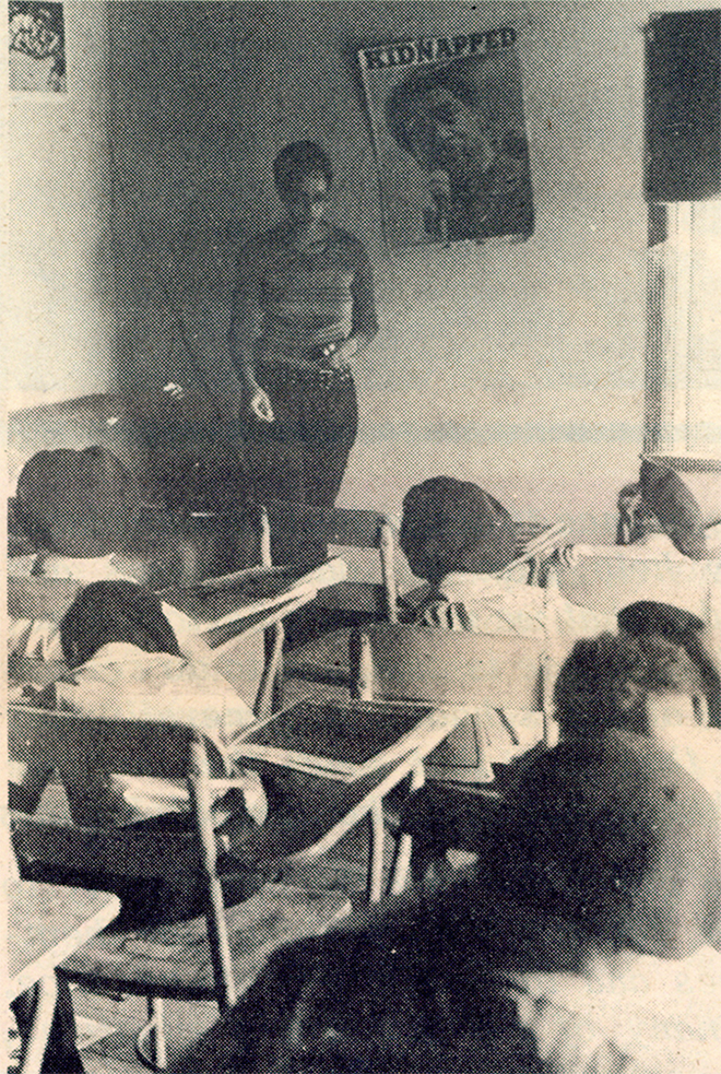 A teacher is standing in front of a classroom full of children
